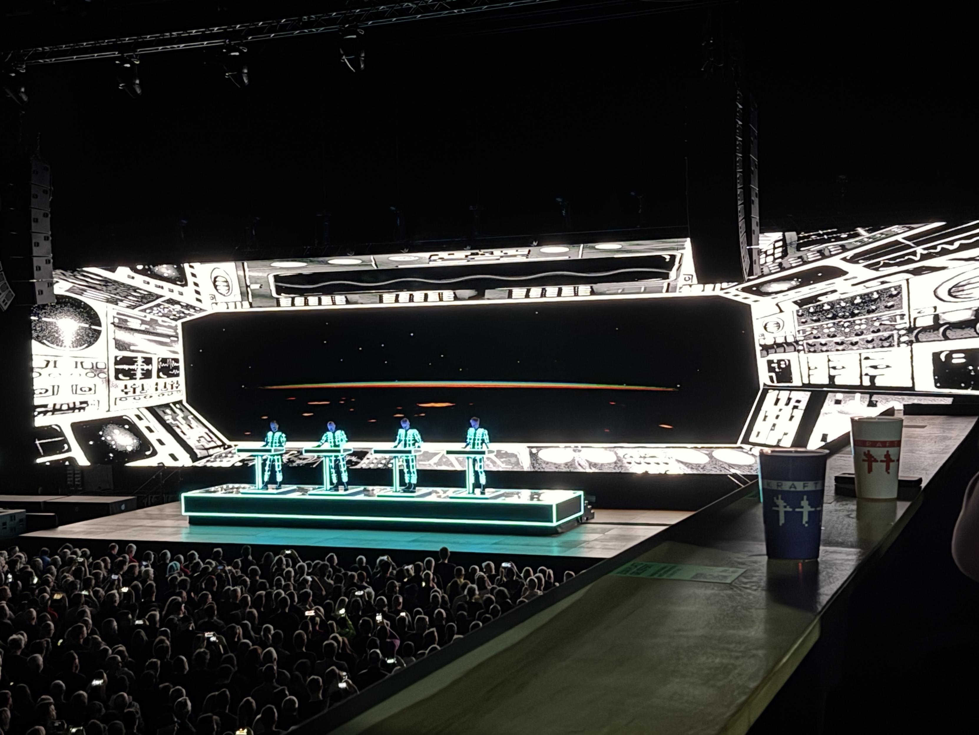 Artists in light blue/turquoise while the projection shows the view out of a spaceship onto a planet