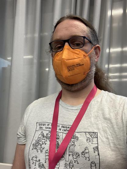 Selfie with glasses, orange ffp2 mask, light grey tshirt, pink lanyard